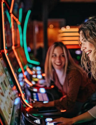 Girl friends gambling in casino on slot machinery