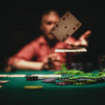 One mature man playing poker late by night, throwing playing cards on table.