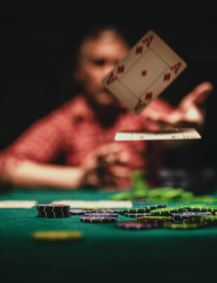 One mature man playing poker late by night, throwing playing cards on table.