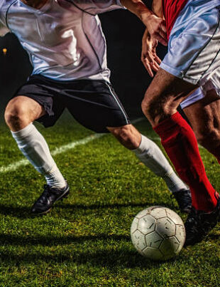 Two soccer players challenging for the ball, low angle view.